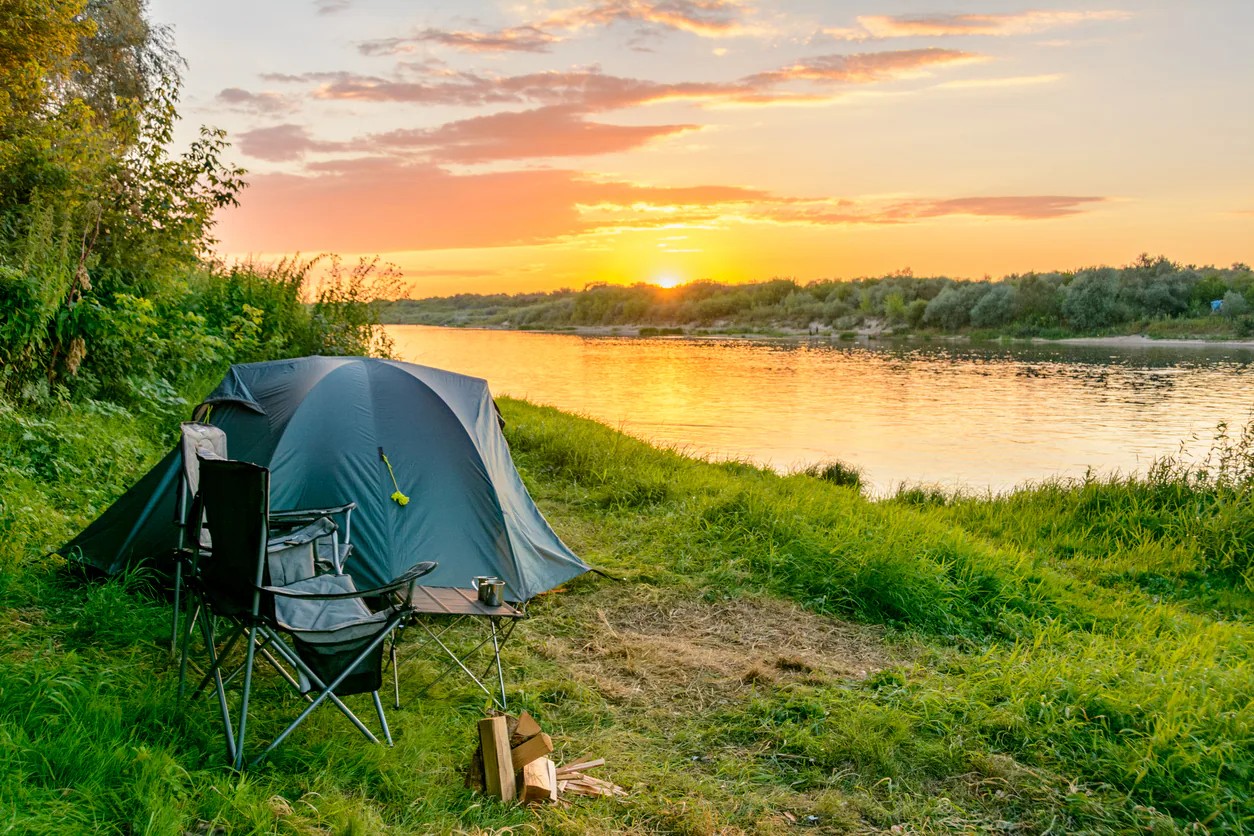 Tente de camping au bord d'une rivière au coucher du soleil